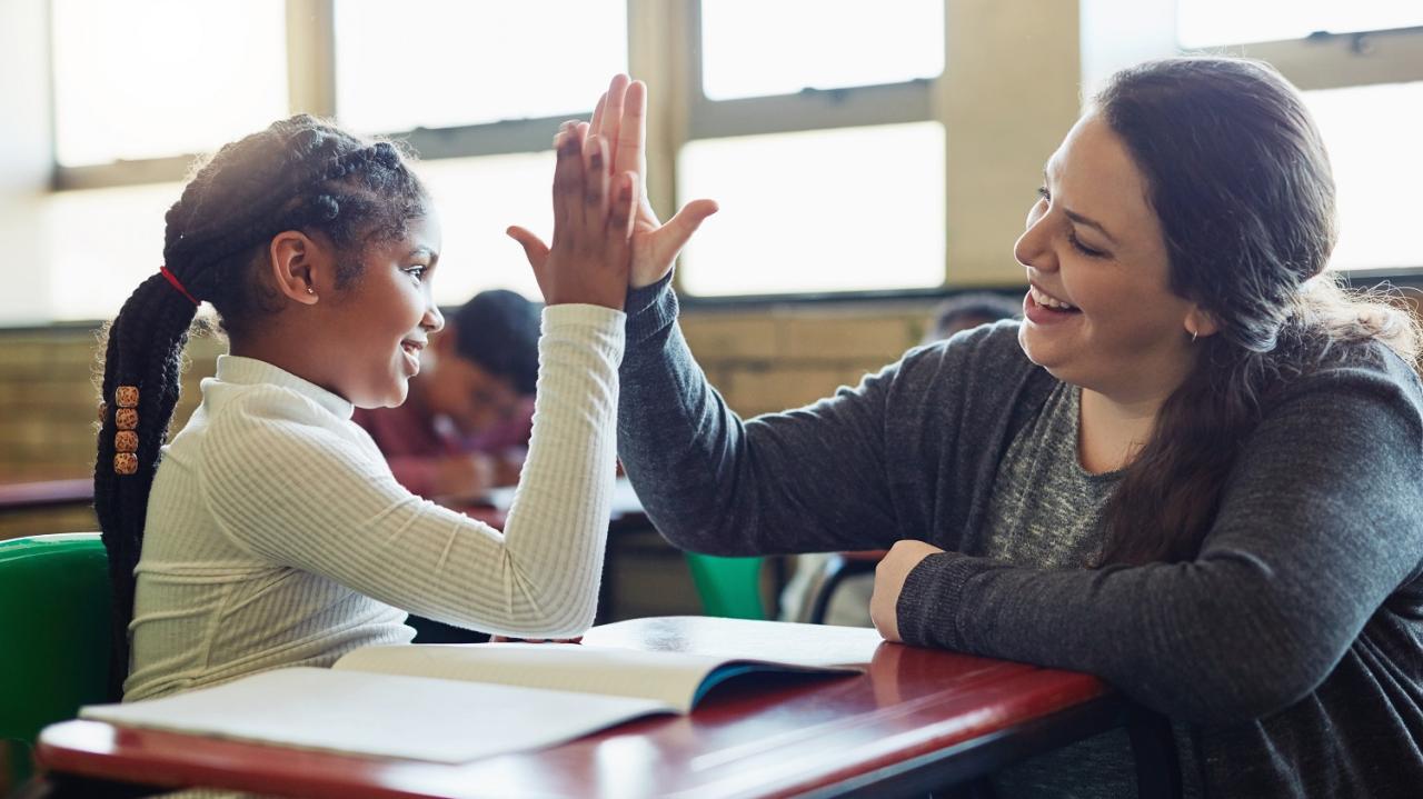Eine Lehramtsanwärterin und eine Schülerin klatschen sich ab (High Five)